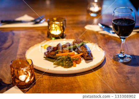 Beef steak meat with vegetables and sauce served with red wine and candles 133308902