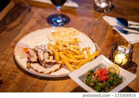 Plate with Gyros meat, pita bread, side salad and french fries on table in Greek restaurant kitchen 133308910