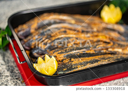 Fish fresh marinated fish with sweet onions, lemon and rosemarin in oven tray and baking paper ready to cook Fish fresh marinated fish with sweet onions, lemon and rosemarin in oven tray and baking paper ready to cook 133308918