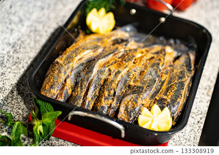 Fish fresh marinated fish with sweet onions, lemon and rosemarin in oven tray and baking paper ready to cook Fish fresh marinated fish with sweet onions, lemon and rosemarin in oven tray and baking paper ready to cook 133308919