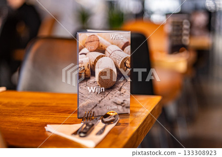 Modern trendy wooden silver appliances - fork and knife on a wooden serving table in the restaurant with a wine card 133308923