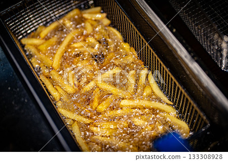French fries cooking. Grid with strips of potato lowered into boiling oil. The concept of fast food, delicious food, restaurant 133308928