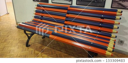 A park bench made of wooden posts painted to resemble large pencils, with a multiplication table printed on each. Concept for modern park design, school education, and leisure. A park bench made of wooden posts painted to resemble large pencils, with a multiplication table printed on each. Concept for modern park design, school education, and leisure. 133309483