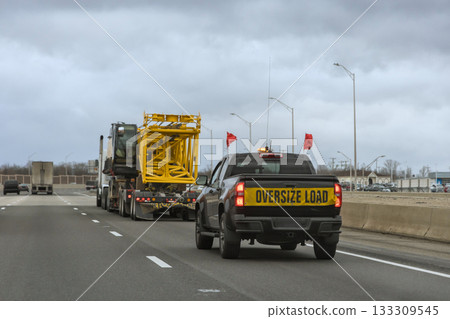 Oversized load being escorted on American highway by safety vehicle Oversized load being escorted on American highway by safety vehicle 133309545