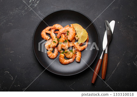 Cooked grilled shrimps lemon parsley black plate seafood appetizer black background 133310018