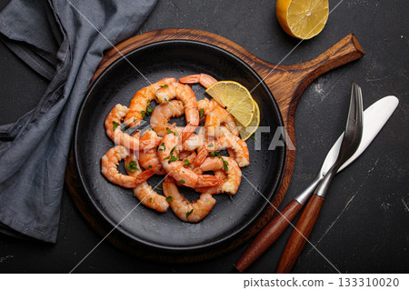 Cooked grilled shrimps lemon parsley black plate seafood appetizer black background Cooked grilled shrimps lemon parsley black plate seafood appetizer black background 133310020