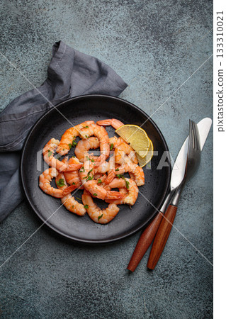 Cooked grilled shrimps lemon parsley black plate seafood appetizer black background 133310021