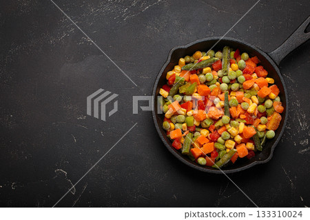 Frozen mixed vegetables cast iron skillet black background healthy cooking defrosting copy space 133310024