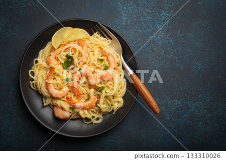 Spaghetti pasta shrimps parsley lemon seafood meal black plate dark blue background copy space Spaghetti pasta shrimps parsley lemon seafood meal black plate dark blue background copy space 133310026