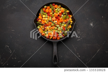 Frozen mixed vegetables cast iron skillet black background healthy cooking defrosting 133310028