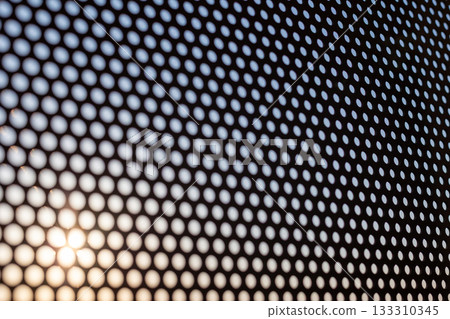 Perforated metal through which the evening sky shines 133310345