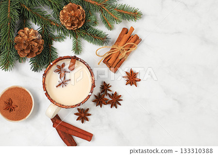 Eggnog with cinnamon and nutmeg for Christmas and the holidays on a marble table with fir branches. A warming eggnog during the cold season, a festive arrangement for Christmas Eve 133310388
