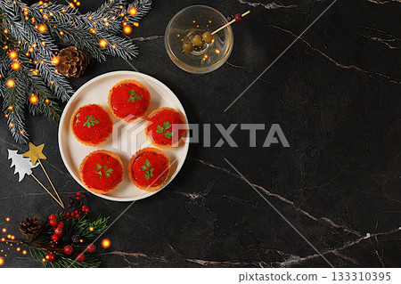Christmas and New Year's dishes, a canap set for the festive table. A plate of p t tartlets and red caviar on a concrete table with a glass of wine and olives, Christmas Eve concept, restaurant menu Christmas and New Year's dishes, a canap set for the festive table. A plate of p t tartlets and red caviar on a concrete table with a glass of wine and olives, Christmas Eve concept, restaurant menu 133310395