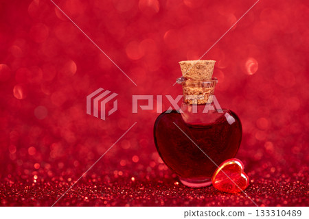Heart-Shaped Glass Bottle with Red Liquid on Glittery Background for Valentines Day Celebration 133310489