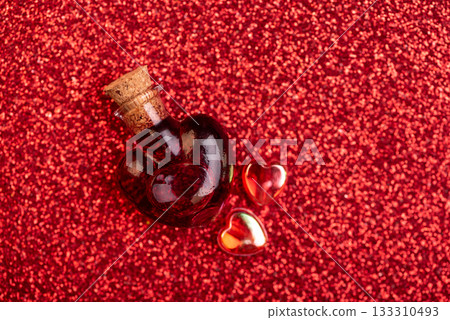 Heart-Shaped Glass Bottle with Red Liquid on Glittery Background for Valentines Day Celebration 133310493
