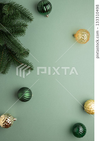 Fir Tree Branch with Green and Golden Christmas Ornaments on Green Background in Festive Flat Lay Fir Tree Branch with Green and Golden Christmas Ornaments on Green Background in Festive Flat Lay 133310498