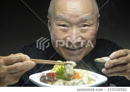 An elderly man eating hot oyster hotpot with a smile An elderly man eating hot oyster hotpot with a smile 133310562