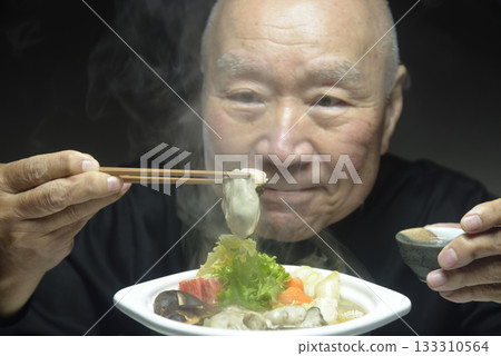 An elderly man eating hot oyster hotpot with a smile An elderly man eating hot oyster hotpot with a smile 133310564