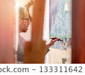 Artist man working on a painting in the studio 133311642