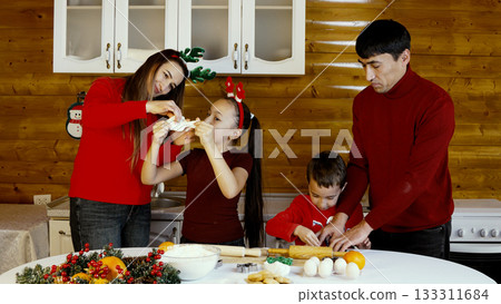 Family are decorating a Christmas cake in the kitchen 133311684