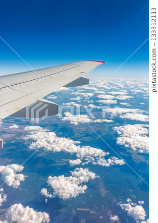 View from the airplane window at a beautiful cloudy sky and the airplane wing 133312113