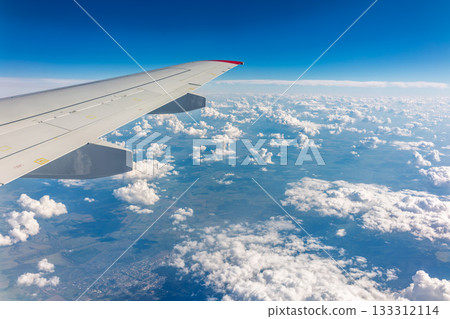 View from the airplane window at a beautiful cloudy sky and the airplane wing 133312114