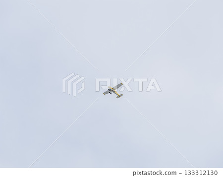 Small ultralight airplane with overhead wing and single propeller flying in sunset sky. Small ultralight airplane with overhead wing and single propeller flying in sunset sky. 133312130
