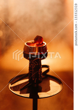 Hookah bowl with glowing coal and drifting smoke in warm bokeh bar light 133312319