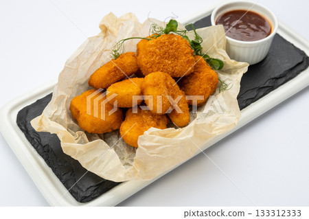 Crispy chicken nuggets with dipping sauce on slate tray, studio top view Crispy chicken nuggets with dipping sauce on slate tray, studio top view 133312333