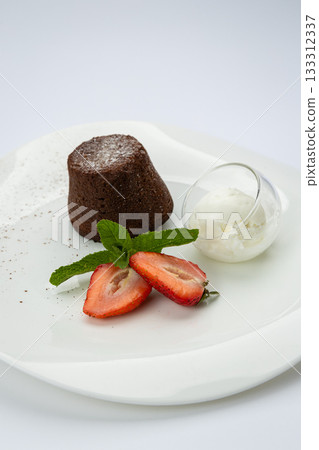Chocolate lava cake with vanilla ice cream and strawberries on white plate, top view Chocolate lava cake with vanilla ice cream and strawberries on white plate, top view 133312337