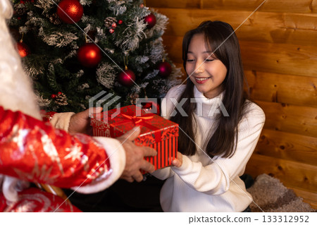 A woman is receiving a Christmas present from as Santa Claus 133312952