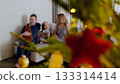 Family enjoying christmas in a cozy living room, with a decorated tree adding warmth and magic to their time together. Night before Christmas. New Year's Eve with family 133314414