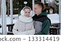 Winter landscape revealing affectionate young couple cuddling, wearing cozy outerwear, sharing intimate embrace amid snow covered park scene 133314419