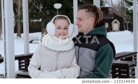 Winter landscape revealing affectionate young couple cuddling, wearing cozy outerwear, sharing intimate embrace amid snow covered park scene Winter landscape revealing affectionate young couple cuddling, wearing cozy outerwear, sharing intimate embrace amid snow covered park scene 133314419