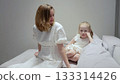 Loving mother comforting crying child on cozy living room sofa, showing gentle support during emotional moment between parent and kid 133314426