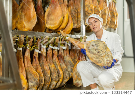 young specialist keeps a large jamon in the workshop 133314447