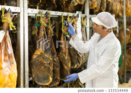 Man employee checks jamon. Quality control Man employee checks jamon. Quality control 133314449