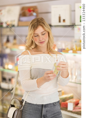 Girl sniffs fragrance of perfume, chooses scent spray Girl sniffs fragrance of perfume, chooses scent spray 133314460