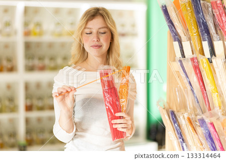 Young woman choosing incense sticks in store 133314464