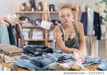 Woman standing in the store and choosing pants and shorts 133314471