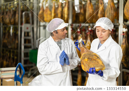 Man and girl worker check jamon, talk and discuss result 133314550