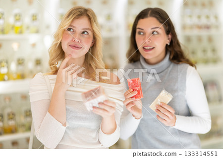 Female consultant helps girl choose craft soap at beauty shop 133314551