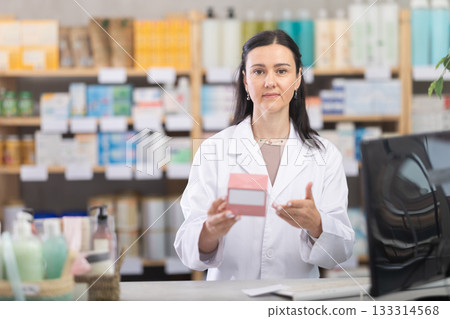 Female pharmacist offers pills and medicines to customers 133314568