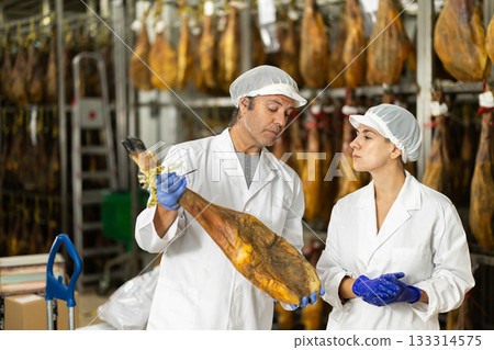 Man and female worker check jamon, discuss result 133314575