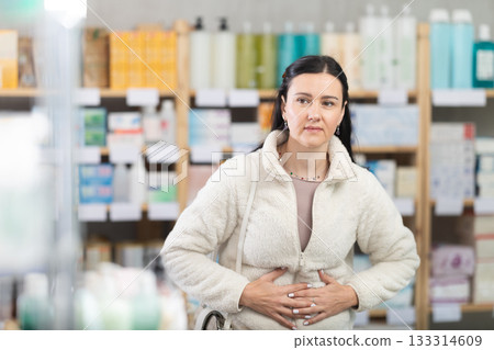 Middle-aged woman having abdominal pain in drugstore Middle-aged woman having abdominal pain in drugstore 133314609