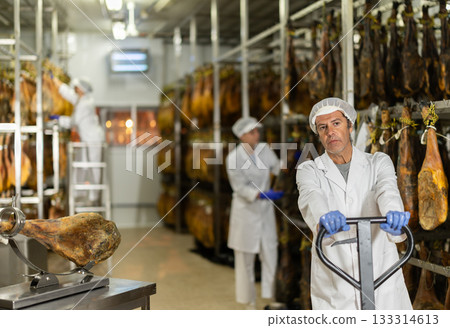 Male worker transports jamon on cart at jamon food factory 133314613