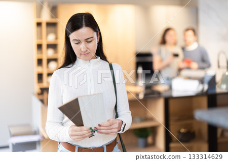 Adult woman choosing wood for floor in furniture salon 133314629