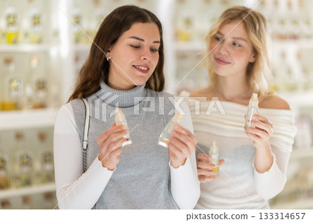 Young woman seller offers perfume to woman buyer Young woman seller offers perfume to woman buyer 133314657