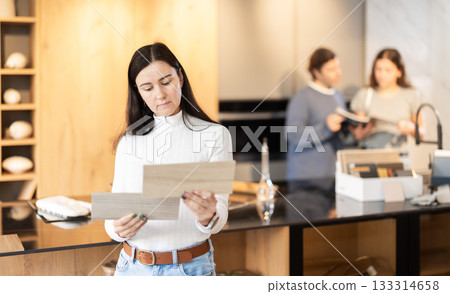 Adult woman choosing wood for floor in furniture salon 133314658