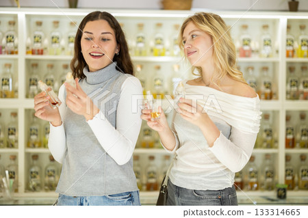 Two girlfriends choose aromatic perfumes together in perfume shop 133314665